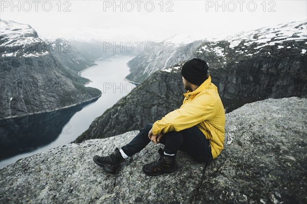 Caucasian man on cliff admiring scenic view of mountain river