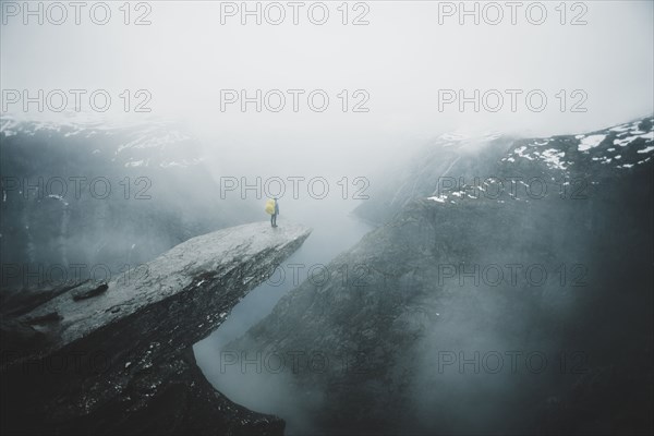 Caucasian man on foggy cliff admiring scenic view of mountain river