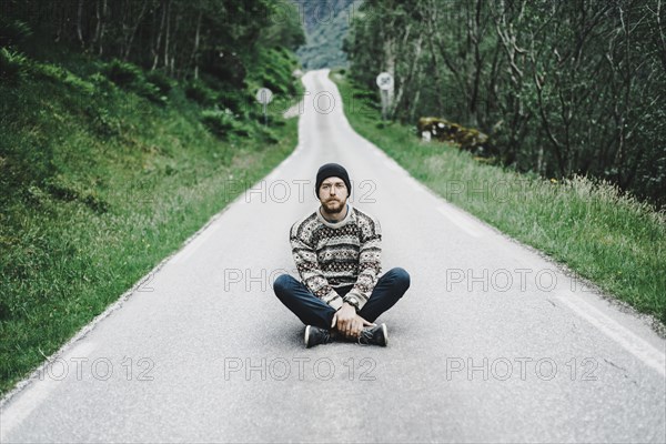 Caucasian man sitting in middle of road