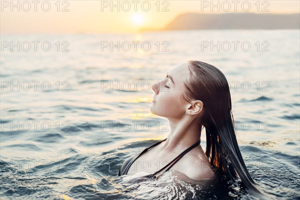 Caucasian woman swimming at sunset