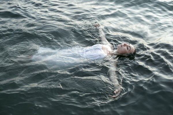 Caucasian woman wearing a dress floating in water