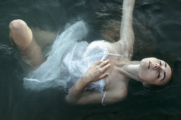 Caucasian woman wearing a dress floating in water