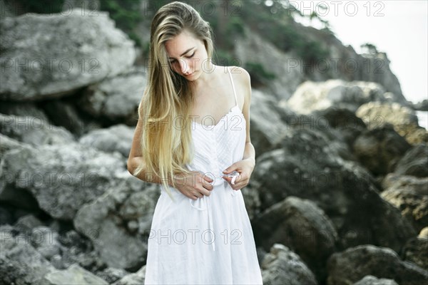 Caucasian woman wearing dress standing on the rocks