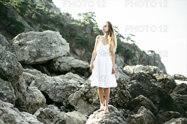 Caucasian woman wearing dress standing on rocks