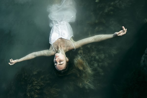 Caucasian woman wearing dress floating in water