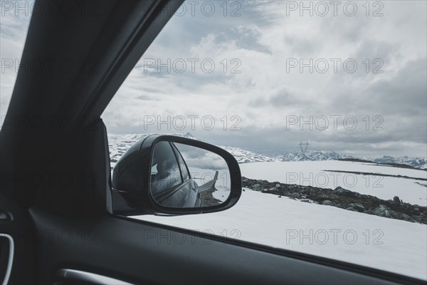Car side-view mirror near winter landscape