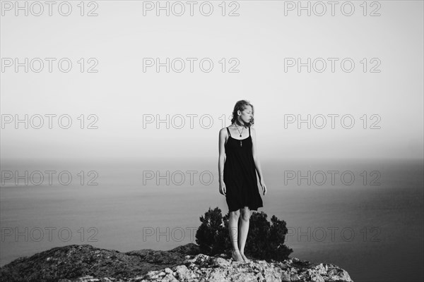 Caucasian woman standing on rock near ocean