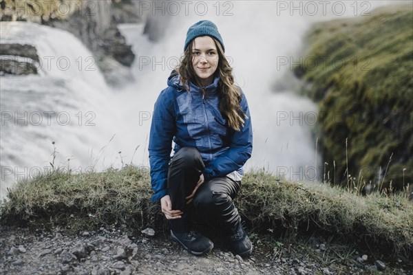 Portrait of smiling Caucasian woman sitting near waterfall