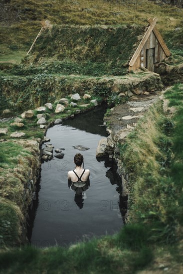 Caucasian woman swimming in pond near rural house