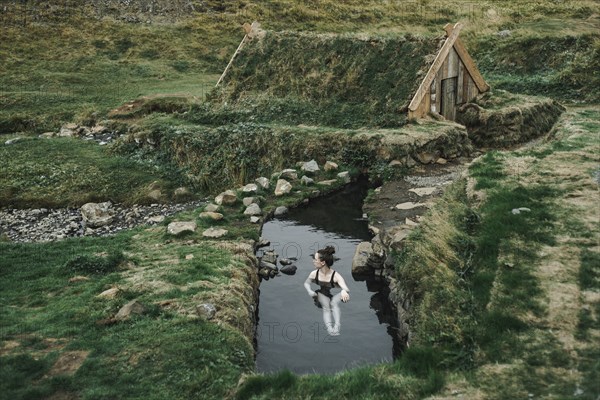 Caucasian woman swimming in pond near rural house