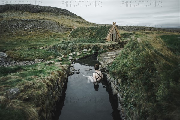 Caucasian woman swimming in pond near rural house