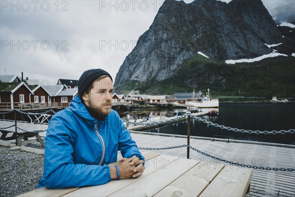 Pensive Caucasian man sitting at table at waterfront