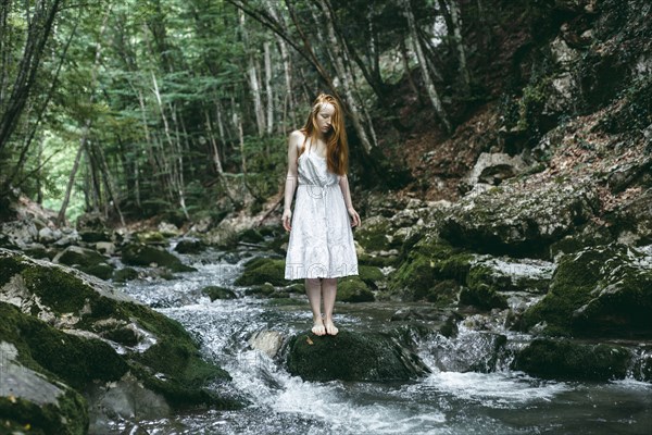 Caucasian woman standing on rock in river