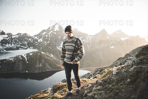 Caucasian man carrying camera near mountain lake