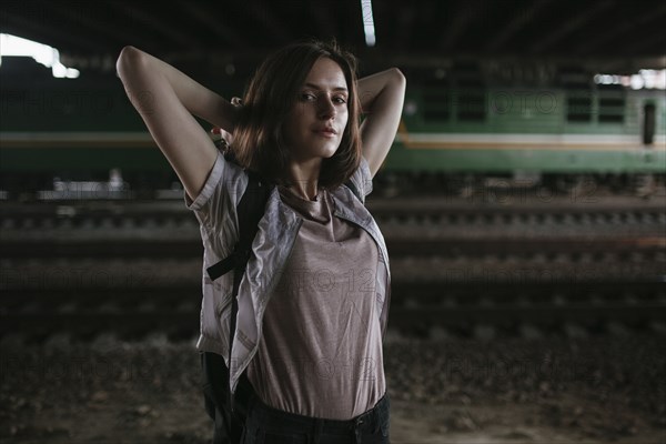 Caucasian woman stretching arms near train tracks at night