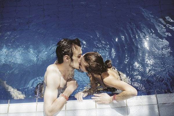 Caucasian couple kissing in swimming pool