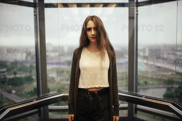 Serious Caucasian woman in glass elevator