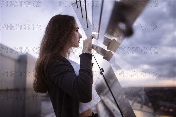 Curious Caucasian woman peering over glass wall at scenic view
