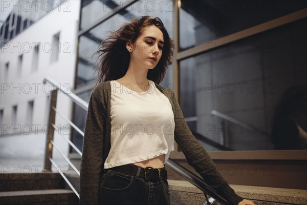 Wind blowing hair of pensive Caucasian woman on staircase