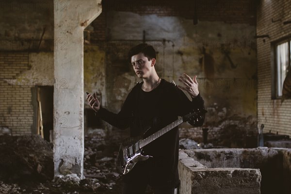 Caucasian man playing guitar in rubble