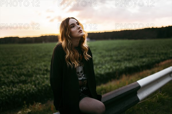 Caucasian woman sitting on guardrail