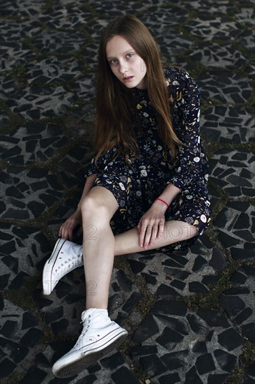 Caucasian woman sitting on stone floor