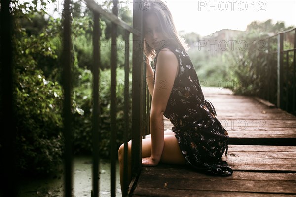 Caucasian woman sitting on wooden bridge