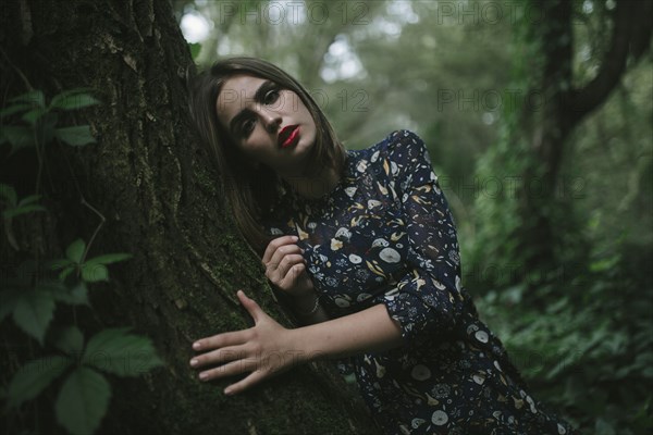 Caucasian woman leaning on tree trunk