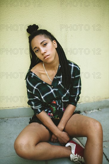 Portrait of serious African American woman sitting on sidewalk