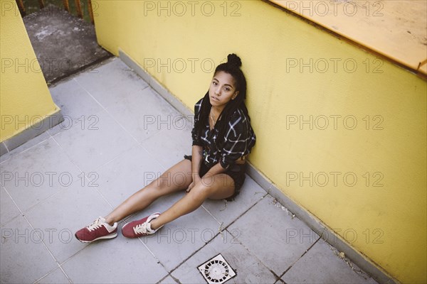 Portrait of serious African American woman sitting on sidewalk