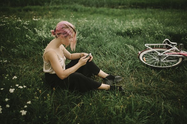 Caucasian woman sitting infield texting on cell phone