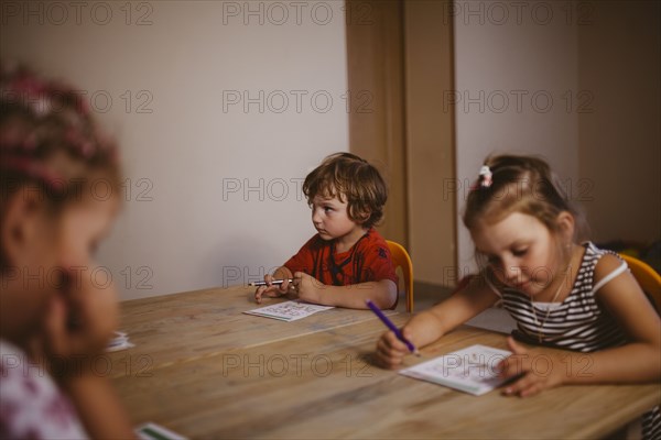 Caucasian boy and girl sitting at table coloring