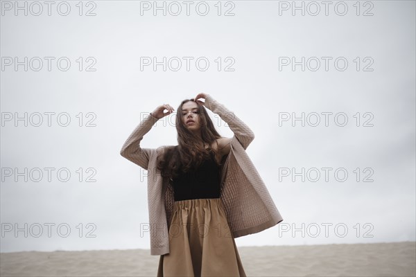 Caucasian woman standing with arms raised at beach