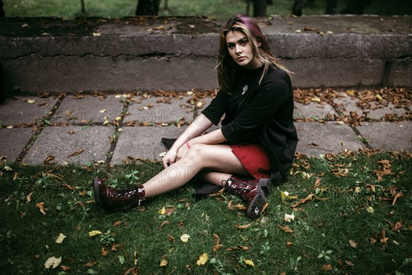 Serious Caucasian woman sitting in autumn leaves