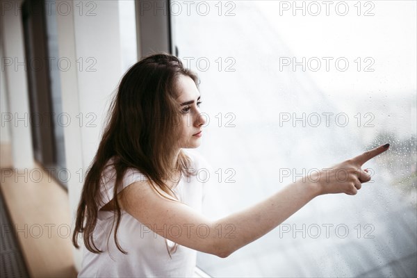 Caucasian woman pointing at rain on window