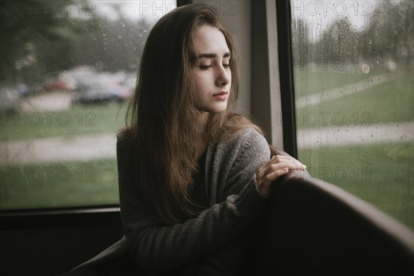 Pensive Caucasian woman sitting on bus in rain