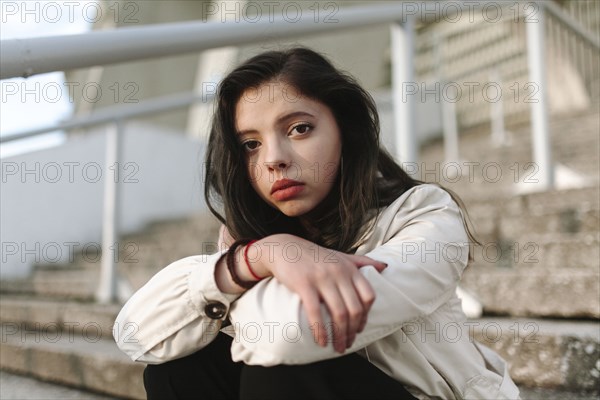 Serious Caucasian woman sitting on staircase