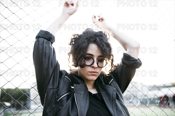 Pensive Caucasian woman leaning on chain-link fence