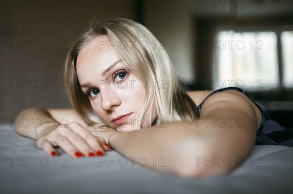 Close up of serious Caucasian woman resting on bed