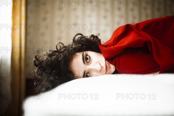 Portrait of serious Caucasian woman laying on bed