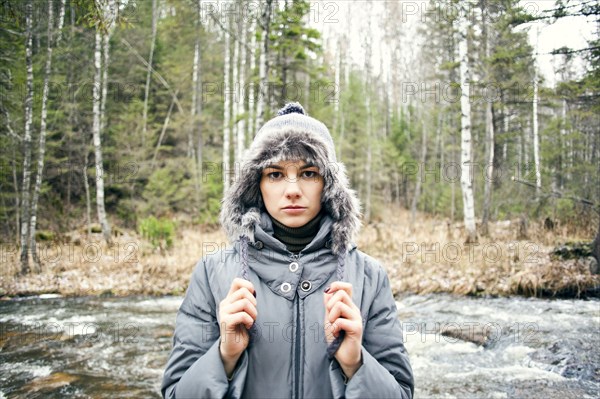 Caucasian woman in coat standing by rural river