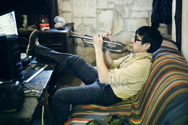 Mari man playing trumpet on sofa