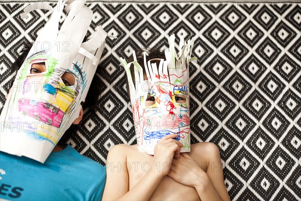 Father and son wearing colorful masks on carpet