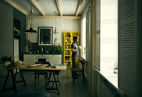 Caucasian man looking out kitchen window