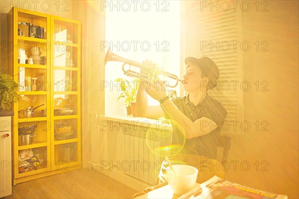 Caucasian man playing trumpet in kitchen