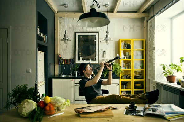 Caucasian man playing trumpet in kitchen