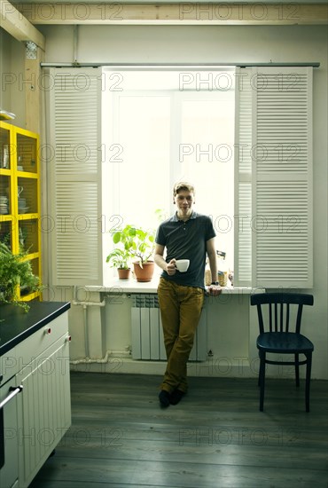 Caucasian man having coffee in kitchen