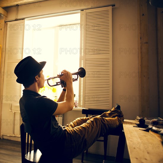 Caucasian man playing trumpet in kitchen