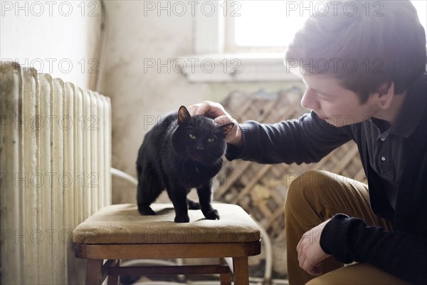 Caucasian man petting cat in living room