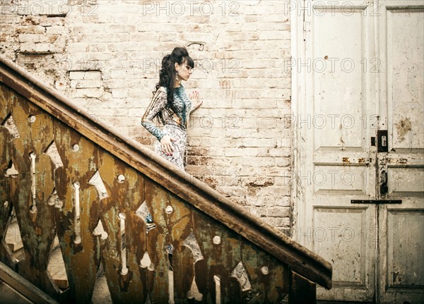 Caucasian woman standing on staircase in dilapidated house